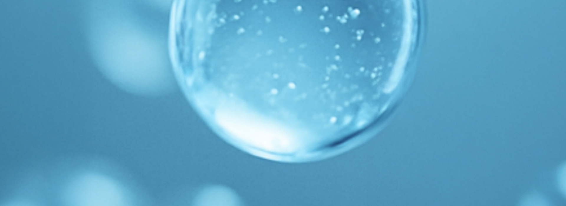 Close-up of a clear bubble with water droplets on a blue background