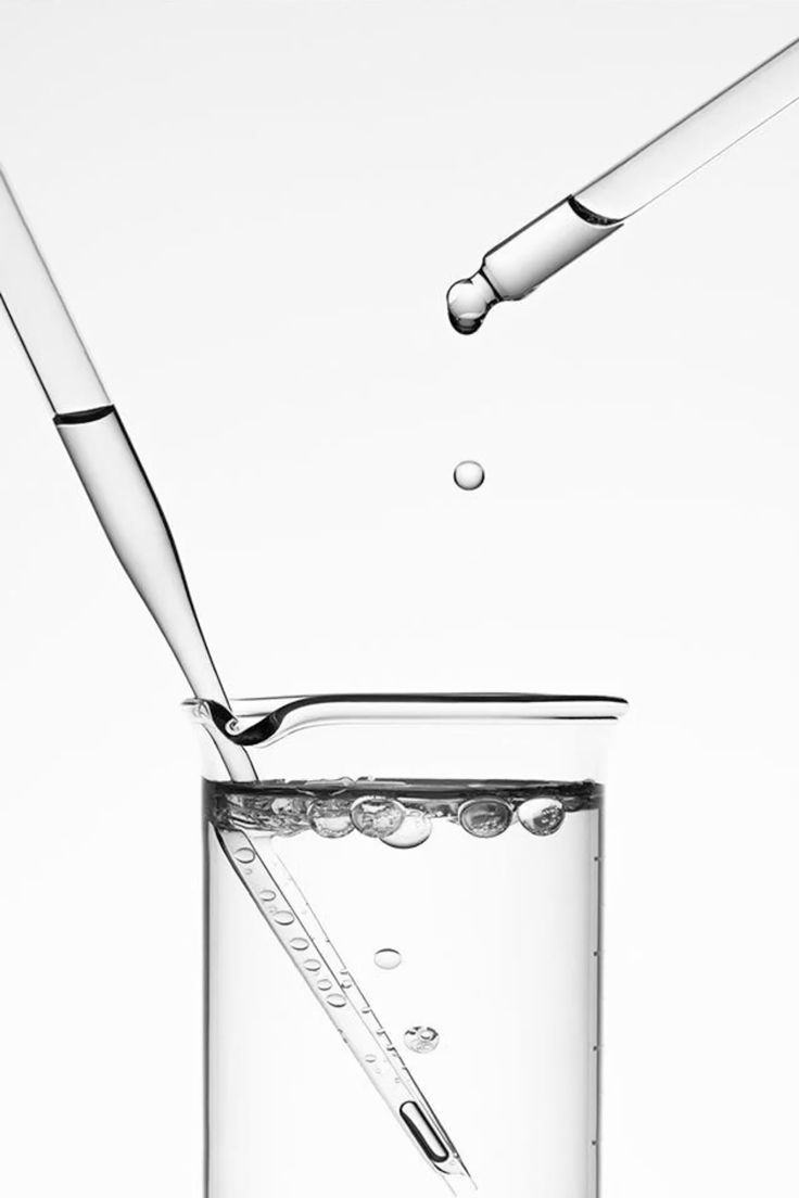 Glass beaker with water and droppers on a white background