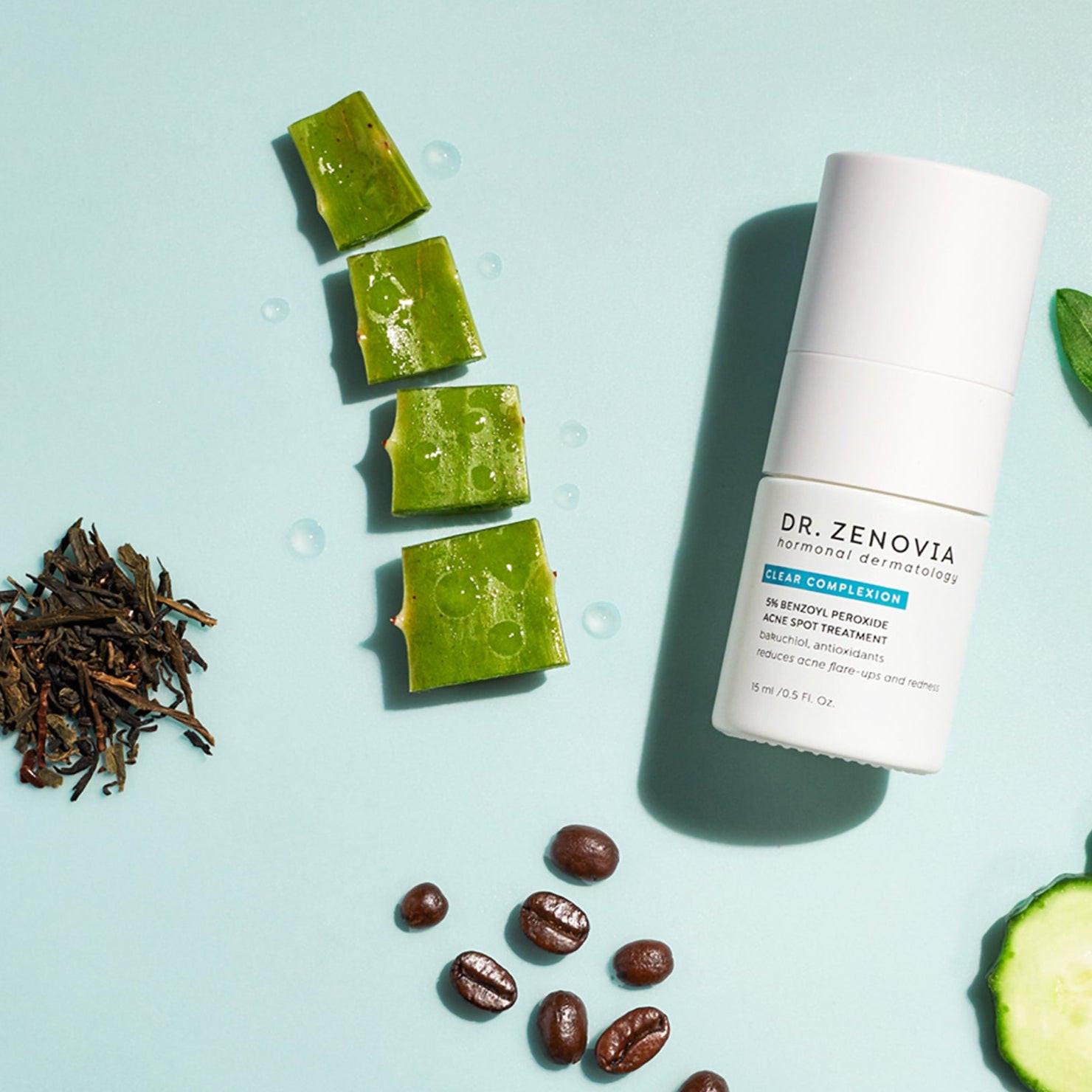 Benzoyl Peroxide Spot Treatment bottle with aloe, coffee beans, cucumber slices, and green leaves on a light blue background