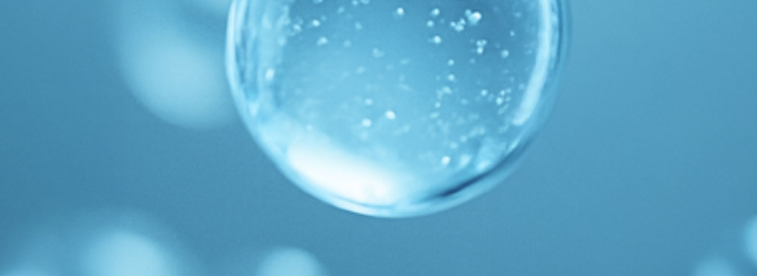 Close-up of a clear bubble with water droplets on a blue background