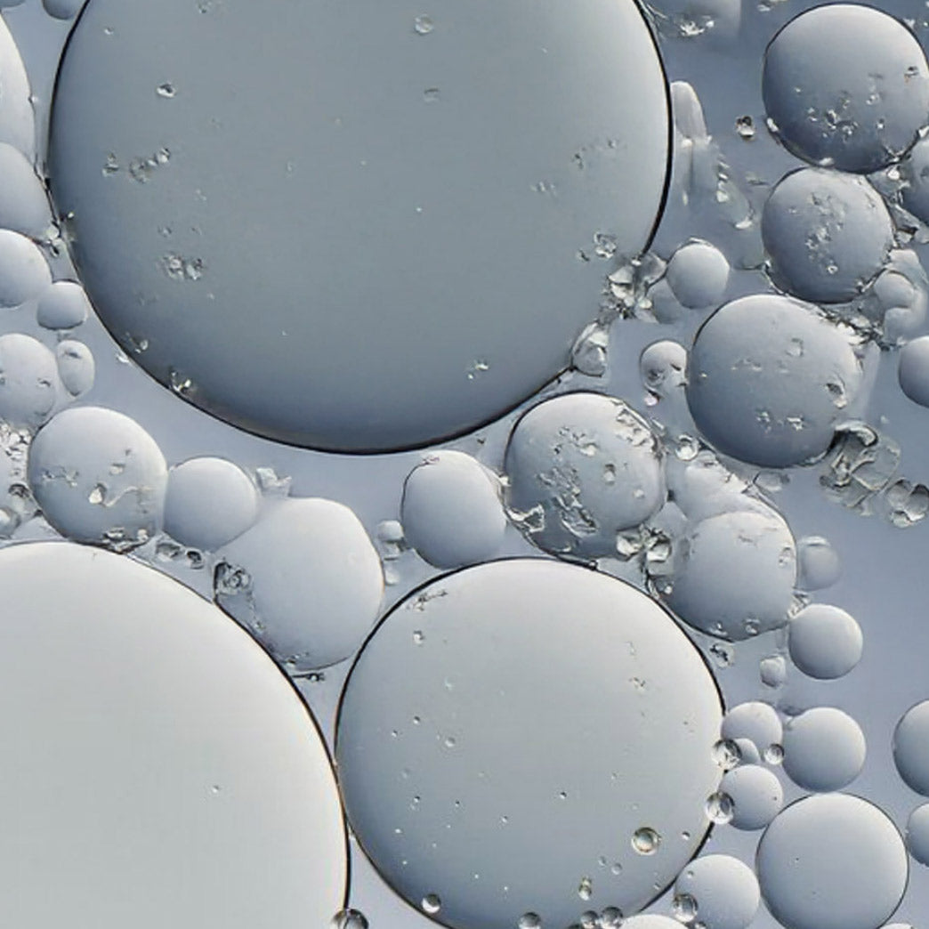 Close-up of oil and water bubbles in a grayish-blue color.