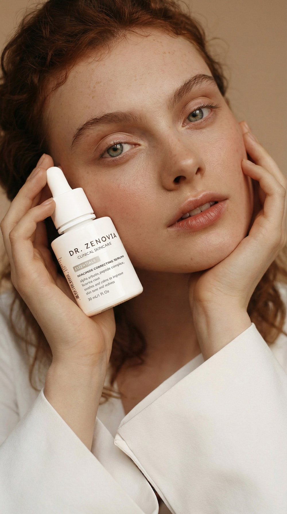 Woman holding a skincare dropper bottle with a neutral background