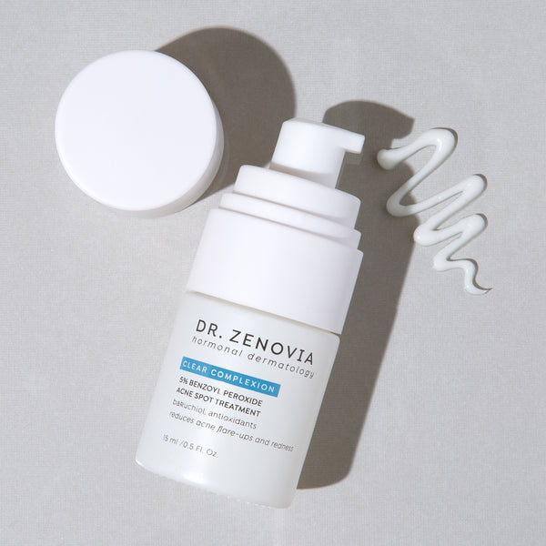 Dr. Zenovia Benzoyl Peroxide Acne Spot Treatment bottle pump with dollop of creamy lotion on neutral background