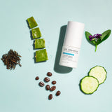 Benzoyl Peroxide Spot Treatment bottle with aloe, coffee beans, cucumber slices, and green leaves on a light blue background