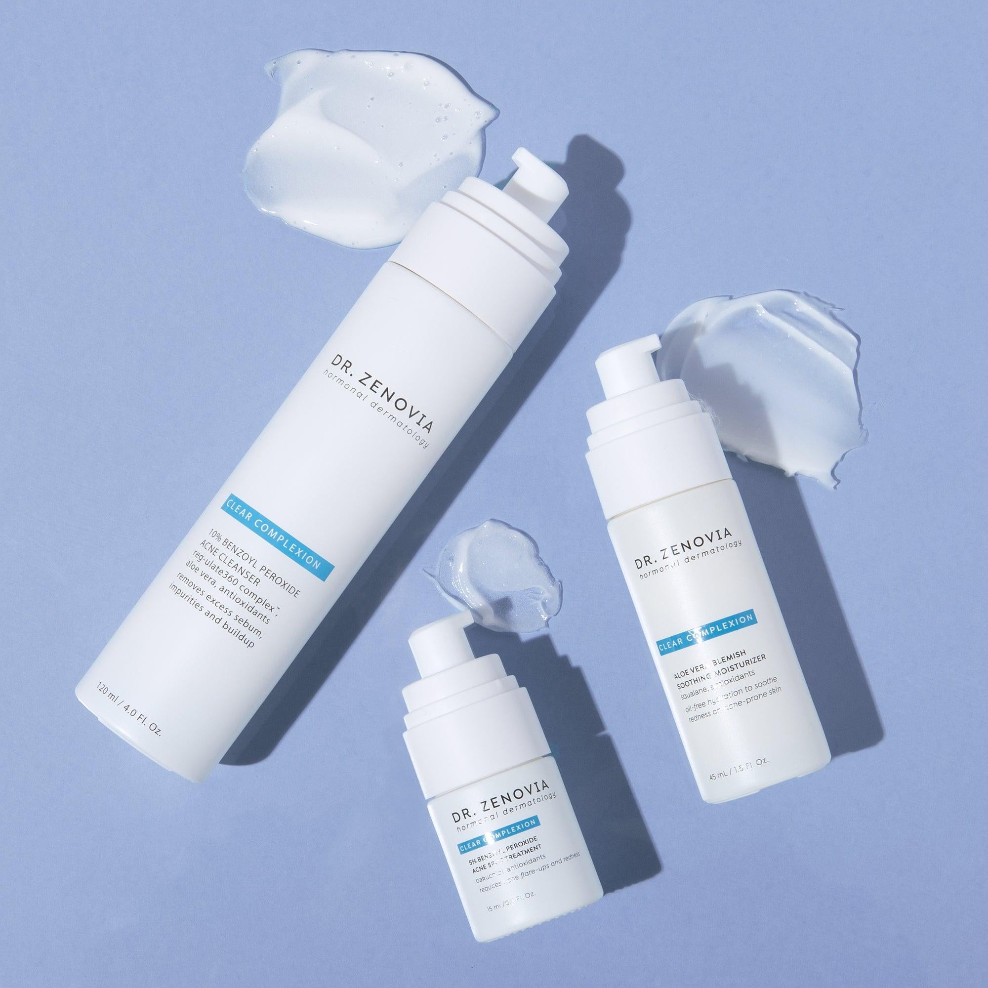 Flat lay of Dr. Zenovia Acne Solutions System products with formula texture smears